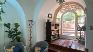 A cozy living room with two armchairs, a glass coffee table, and a bookshelf. - Suite 1744 (Meta)