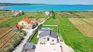 Et kystnære boligområde med huse, vinmarker og et stort vandareal.