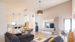 En moderne stue med en hjørnesofa, et sofabord og et tv ophængt på væggen.