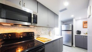 A modern kitchen with a black stove, stainless steel microwave, and refrigerator. - Steps from Beach 2 Bed 2 Full Bath w/PK  @ ESJ (Carolina)