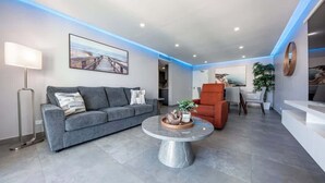 A modern living room with a grey sofa, a round coffee table, and a red armchair. - Steps from Beach 2 Bed 2 Full Bath w/PK  @ ESJ (Carolina)