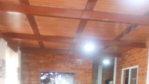 A dining area with a checkered table, red chairs, a brick wall, a television, and a fan. - Casa Campestre Para Descanso o Trabajo con Wifi, Cocina (carmen de apicala)