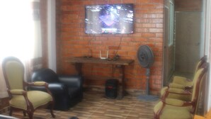 A living room with a brick wall, a flat-screen TV, and wooden flooring. - Casa Campestre Para Descanso o Trabajo con Wifi, Cocina (carmen de apicala)