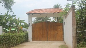 A gated entrance with a tiled roof, surrounded by greenery and a concrete pathway. - Casa Campestre Para Descanso o Trabajo con Wifi, Cocina (carmen de apicala)