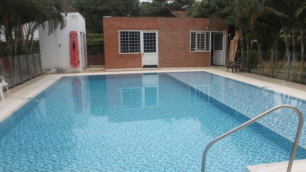 A rectangular swimming pool with a tiled floor and a metal handrail. - Casa Campestre Para Descanso o Trabajo con Wifi, Cocina (carmen de apicala)