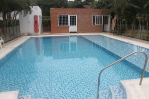 A rectangular swimming pool with a tiled floor and a metal handrail. - Casa Campestre Para Descanso o Trabajo con Wifi, Cocina (carmen de apicala)