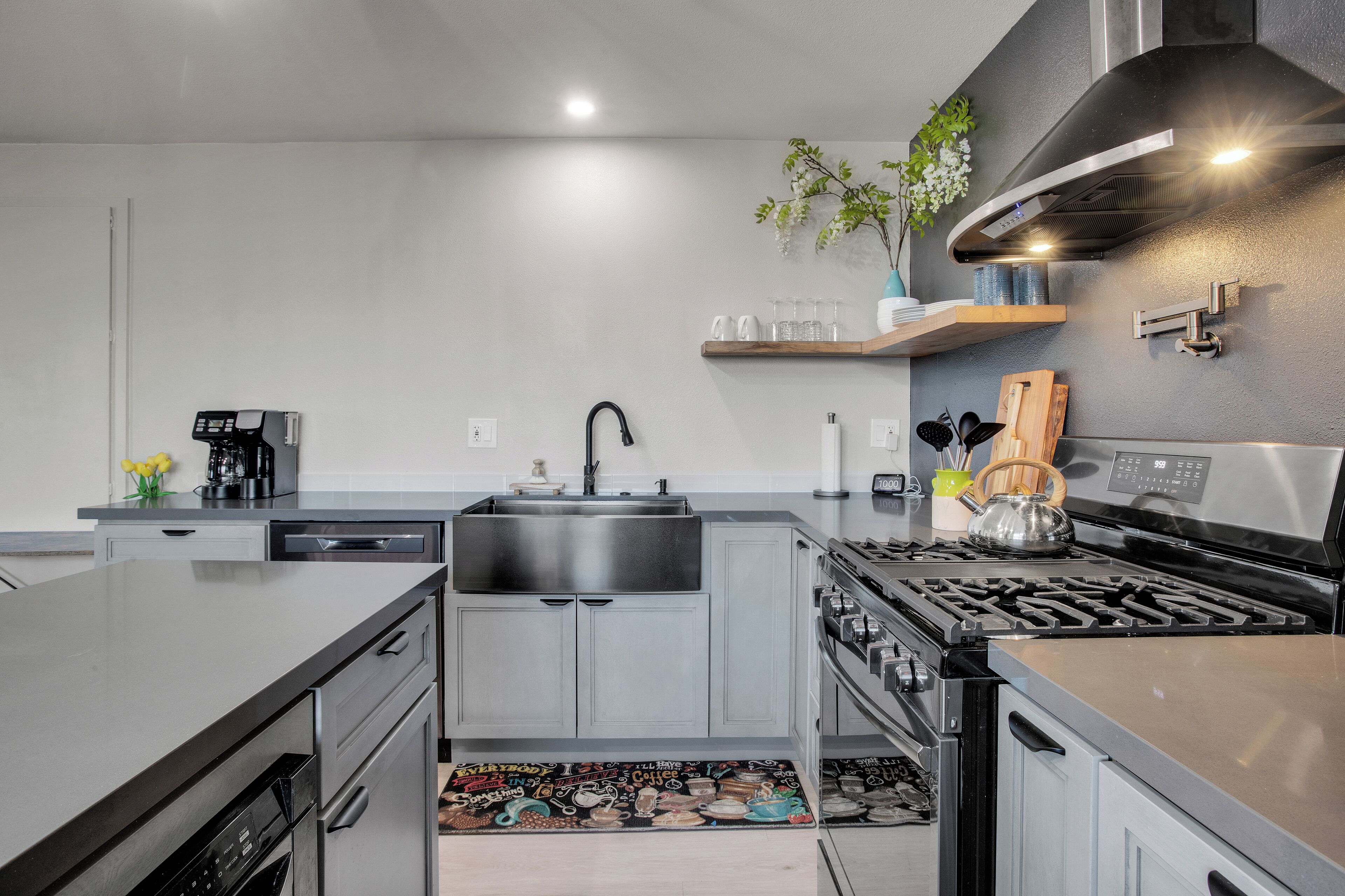 A modern kitchen with grey cabinets, stainless steel appliances, and a black stove.