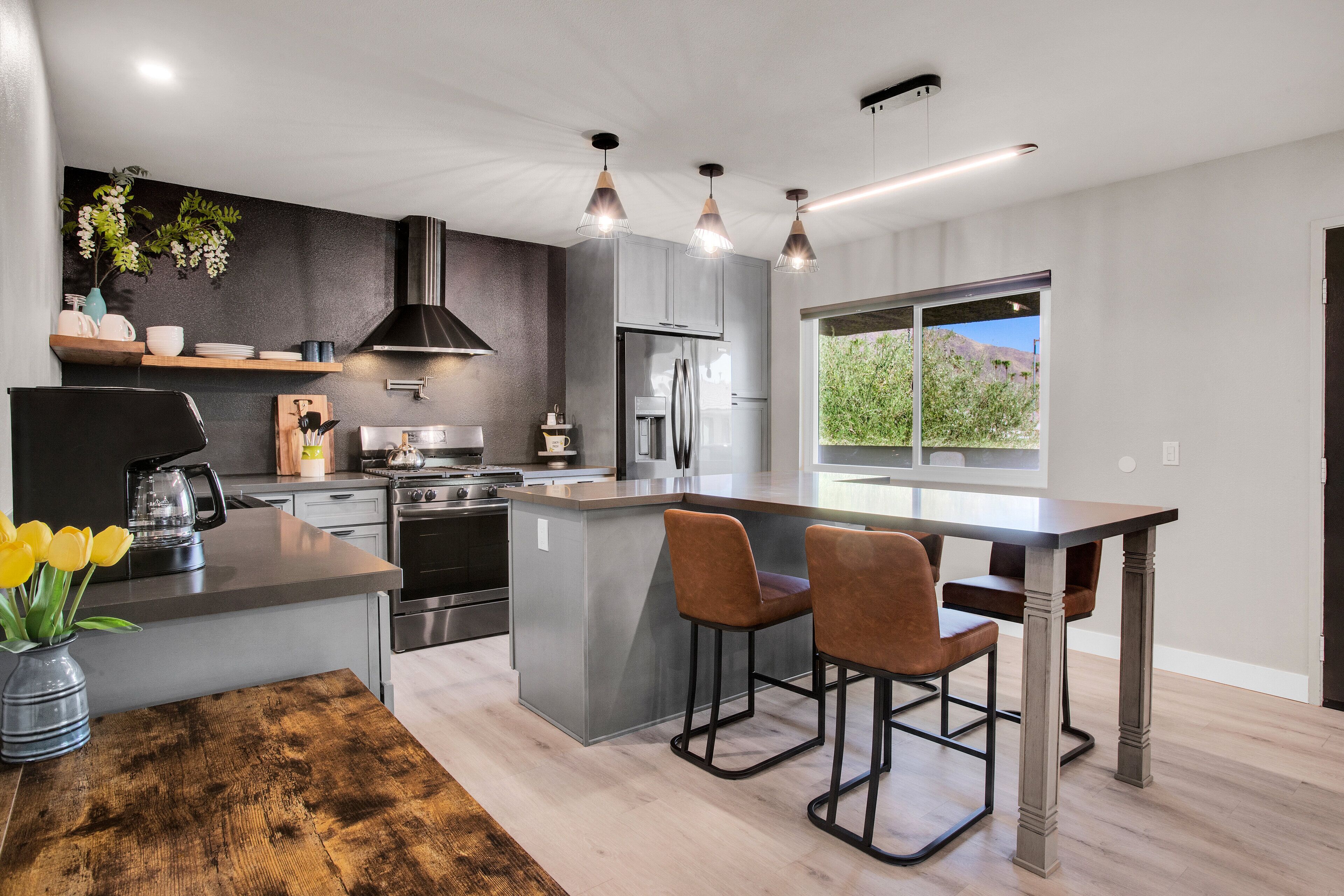 A modern kitchen with a central island, stainless steel appliances, and pendant lighting.