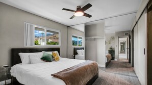 A bedroom with a large bed, a ceiling fan, and a view of a mountain through the window.