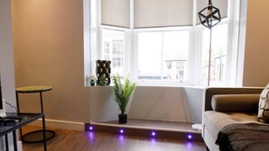 A living room with a large window, a round rug, a sofa, and a small table.