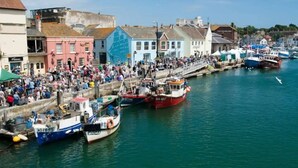 A harbor with boats docked along the waterfront, surrounded by colorful buildings. - Beachside Family Flat, Central Weymouth (Weymouth)