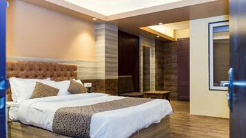 A modern bedroom with a large bed, a wooden headboard, and a seating area with a chair and table.