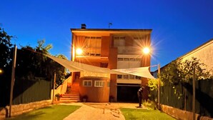 Un edificio de dos pisos con un patio cubierto, un camino de entrada y un césped bien cuidado.