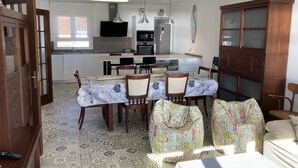 Un comedor con una mesa lista para cuatro personas, rodeada de sillas de madera y un mantel estampado.