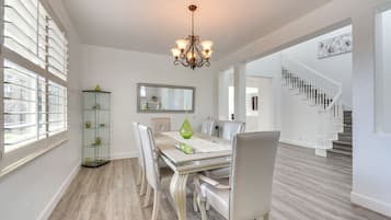 A dining area with a chandelier, a glass display cabinet, and a staircase in the background.