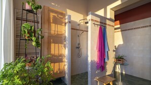 A shower area with a glass-enclosed shower, a wooden door, and a small wooden stool.
