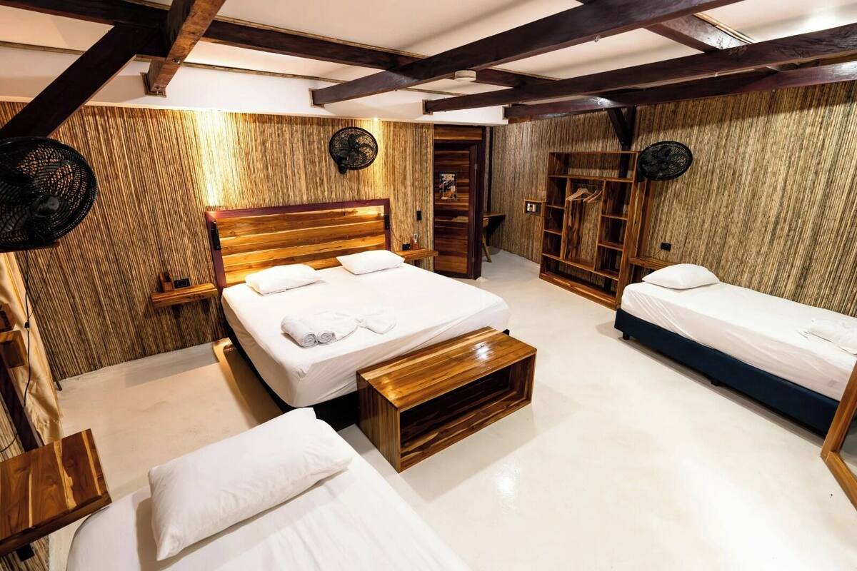 Una habitación con una cama grande, dos camas más pequeñas, muebles de madera y un armario.