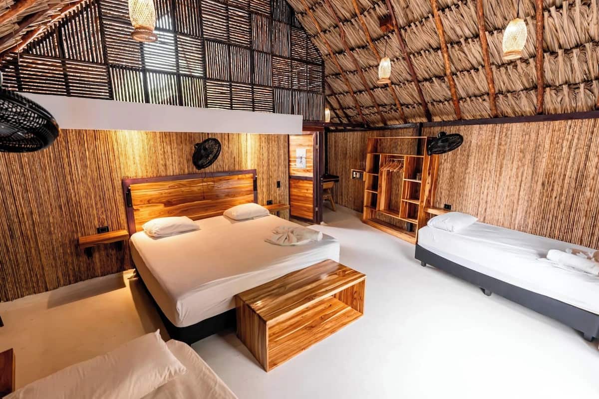 Una habitación con techo alto, paredes de madera, una cama con cabecera de madera, un banco y un armario.
