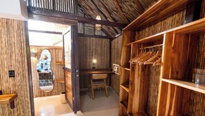 Quarto com paredes de madeira, uma escrivaninha e um cabideiro.