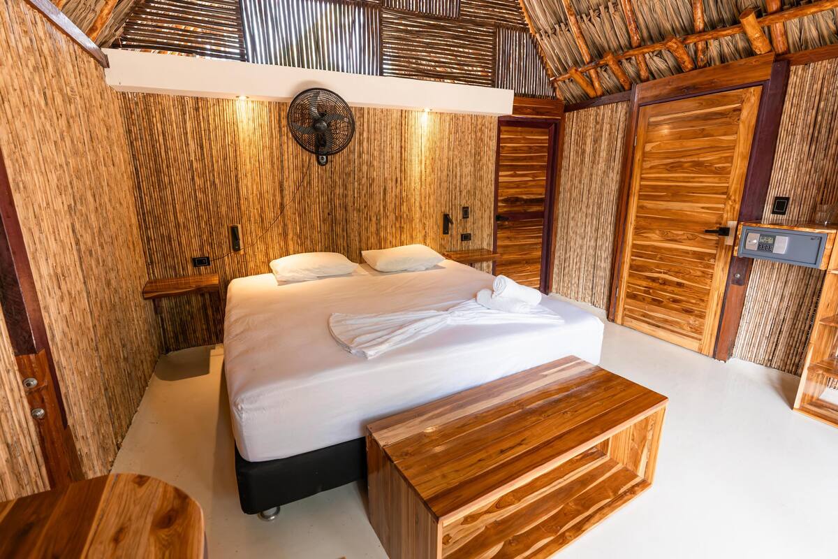 Un dormitorio de estilo rústico con cama, mesitas de noche y ventilador de techo.