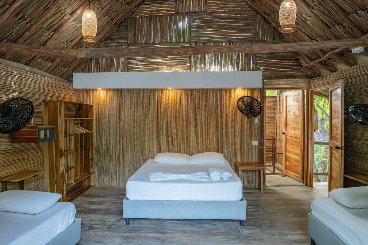Una habitación con cama, paredes de madera y ventilador de techo.