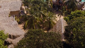 Um resort tropical com cabanas de telhado de palha, palmeiras e vista para o oceano.