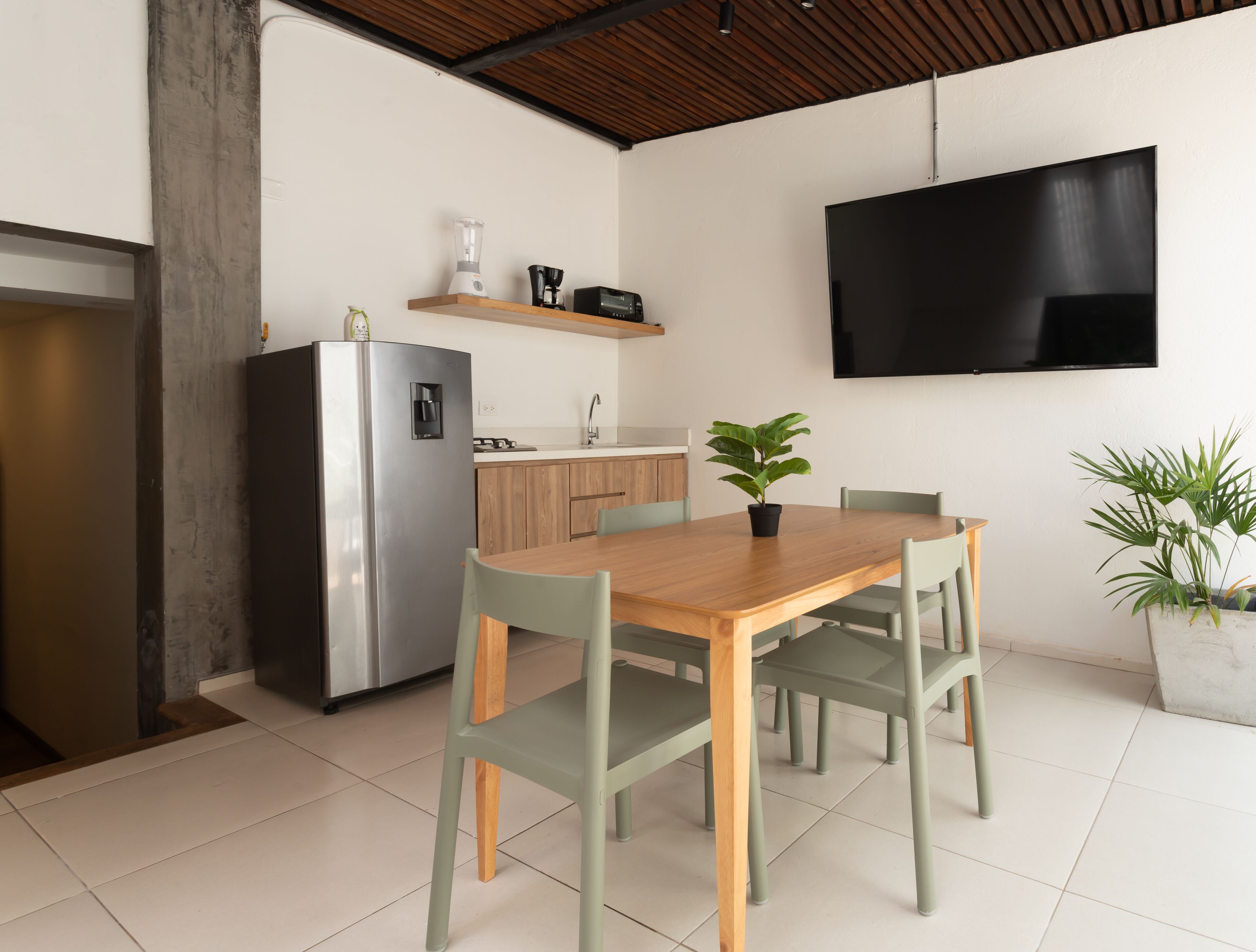A modern kitchen with a built-in refrigerator, a coffee maker, and a flat-screen TV mounted on the wall.