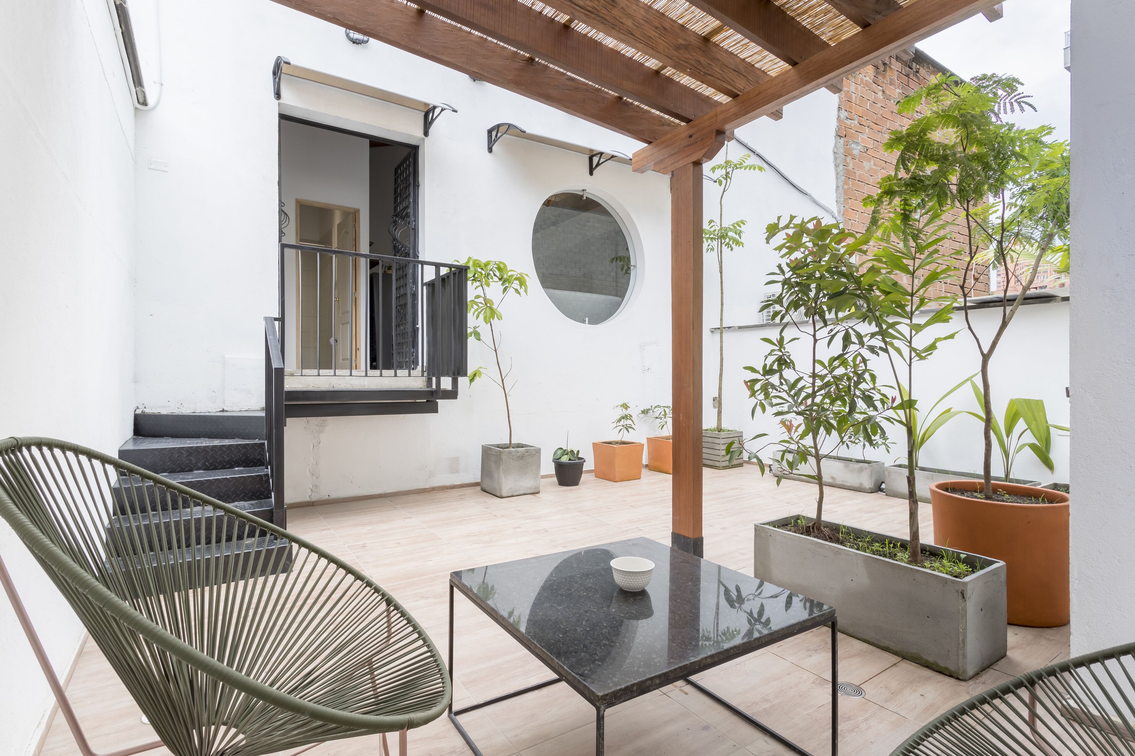 Un patio techado con una mesa, sillas y plantas en macetas.