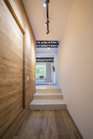 A wooden hallway with a staircase leading to a room with a view of greenery outside. - Soy Local Primavera  (Medellín)