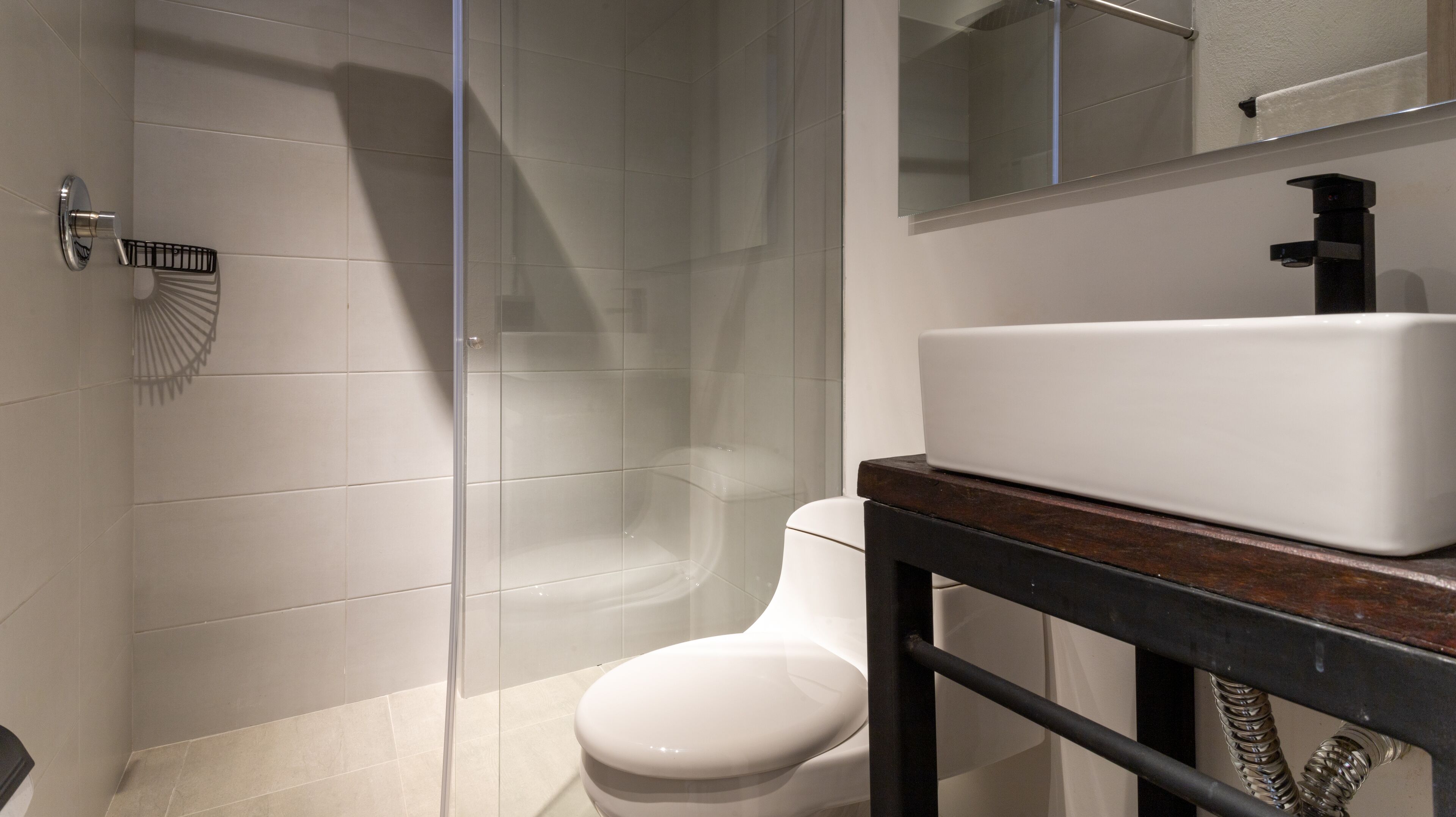 Een moderne badkamer met een douchecabine van glas, een wit toilet en een wastafel op een houten meubel.