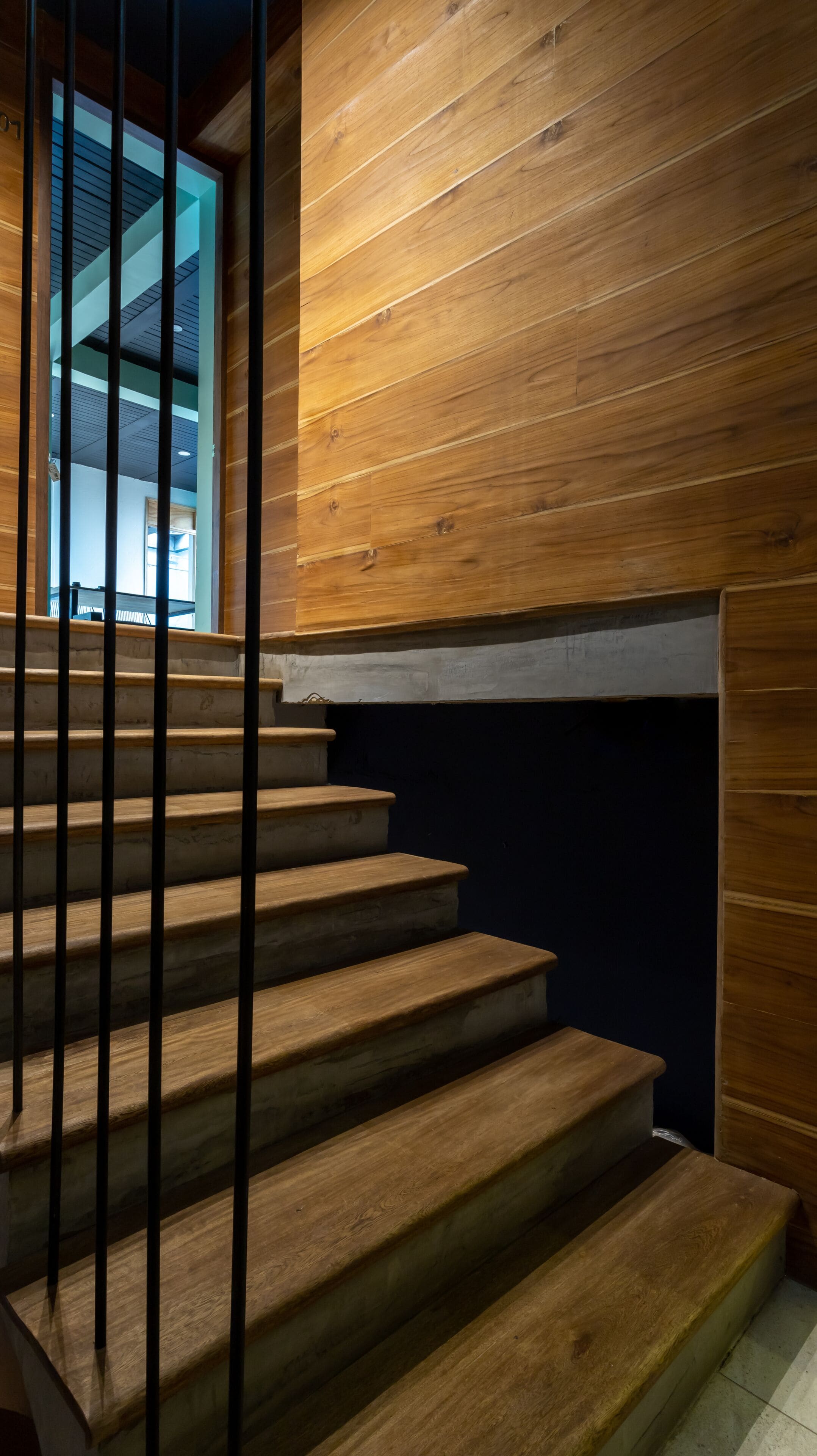 A wooden staircase with metal railings leading to a landing.