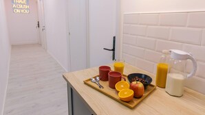 Uma cozinha com bandeja de café da manhã contendo fatias de laranja, um recipiente com cereal, duas canecas, um copo de suco de laranja, uma jarra de leite e um jarro de suco.