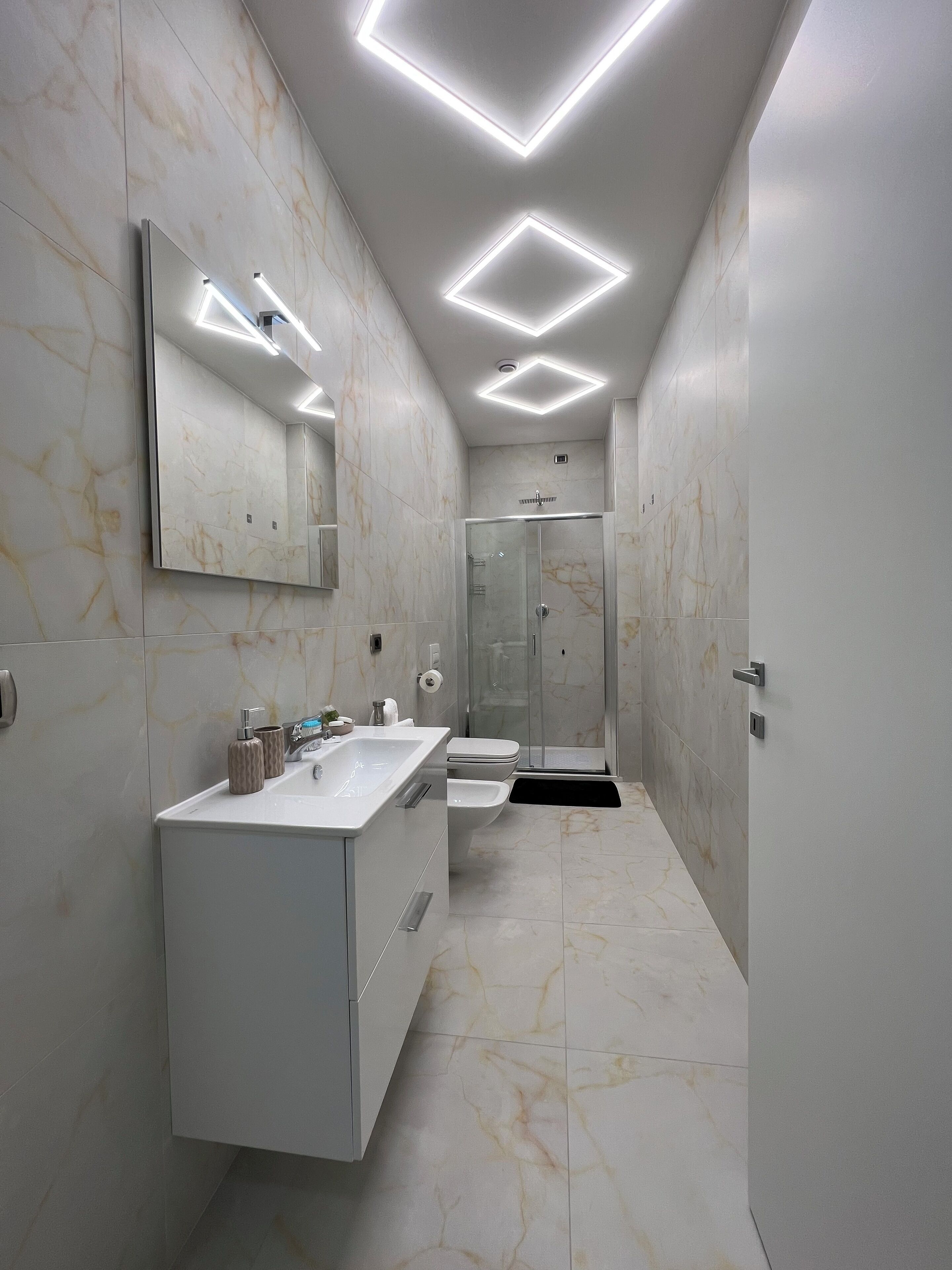 A modern bathroom with a large mirror, a sink, a toilet, and a shower.