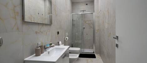A modern bathroom with a large mirror, a sink, a toilet, and a shower.
