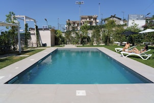 Una piscina al aire libre, sombrillas, tumbonas