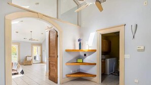 Un vaste espace de vie doté d’un haut plafond, d’une bibliothèque intégrée en bois et donnant sur une autre pièce.