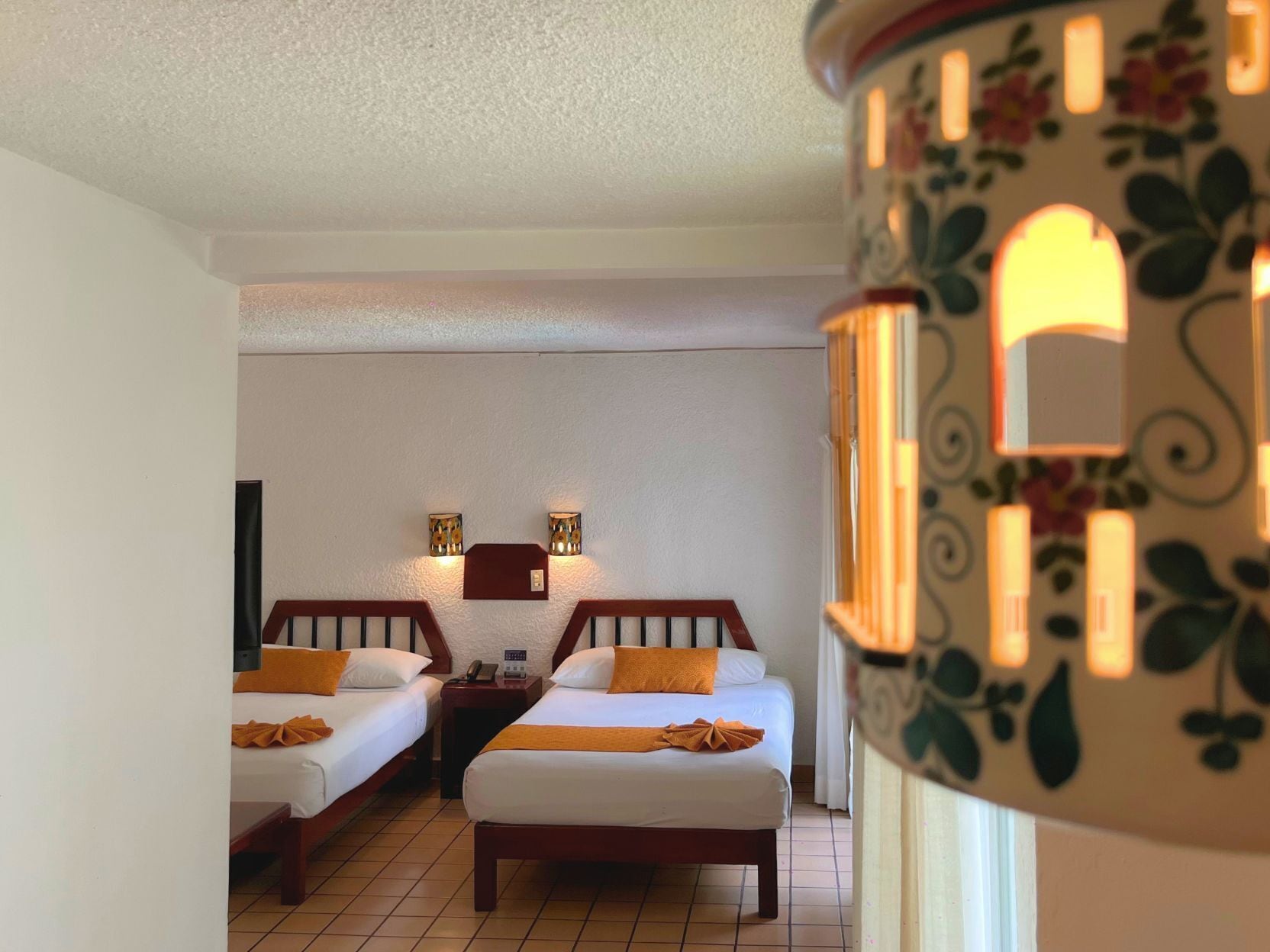 A hotel room with two beds, a small table, and a nightstand.