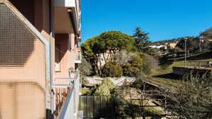 A residential building with a balcony, a staircase, and a view of a hill with trees and houses. - Marina Bike Family Home (Andora)