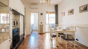 A kitchen with a refrigerator, stove, and a dining area with chairs and a table. - Marina Bike Family Home (Andora)