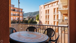 A balcony with a round table and chairs, overlooking a residential area with buildings and hills. - Marina Bike Family Home (Andora)