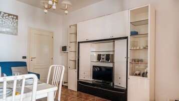 Un espacio habitable compacto con zona de comedor, televisor y armarios empotrados.