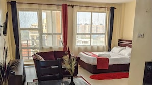 A hotel room with a dining area, a bed, and a view of the city.