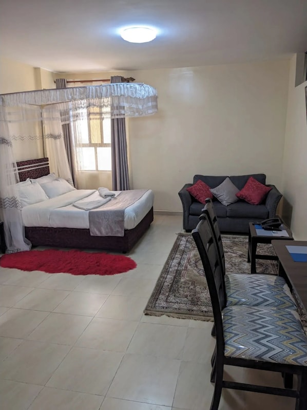 Quarto com cama, mesa de cabeceira, poltrona, sofá e uma pequena mesa.