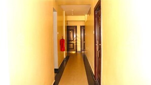 A narrow hallway with yellow walls and a black floor.