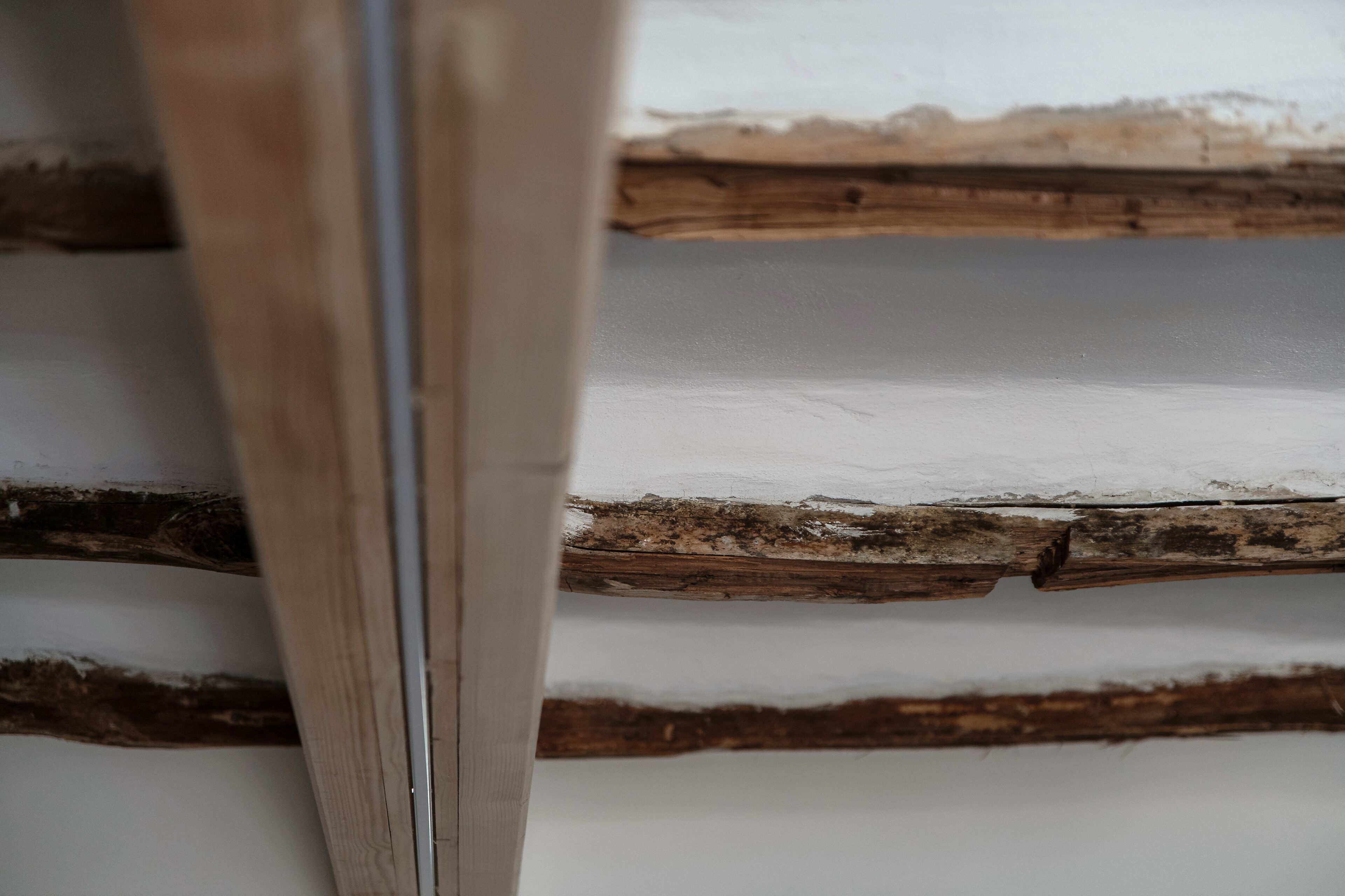 Gros plan sur une structure en bois, avec un mur blanc en arrière-plan.