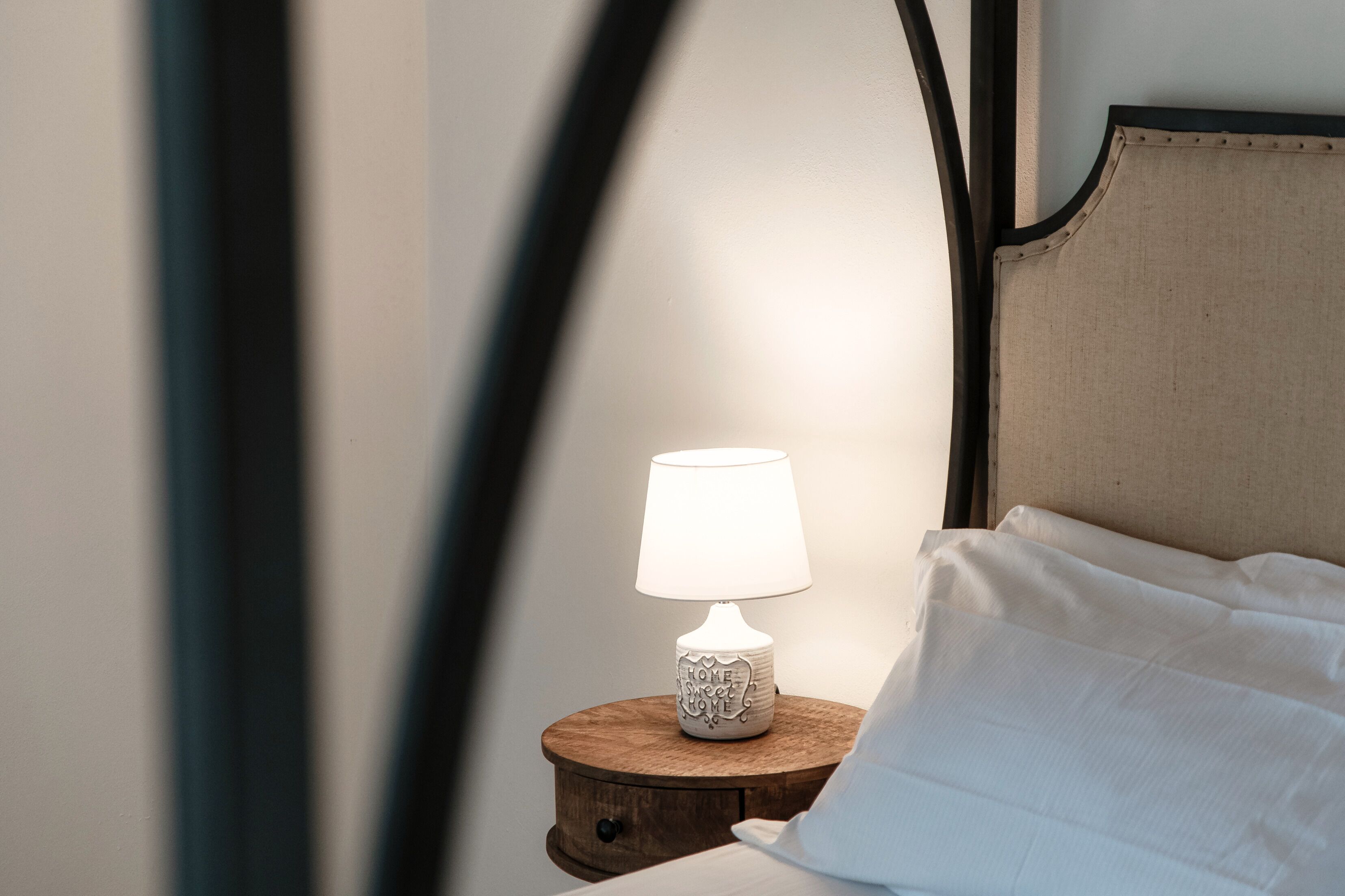 Ein Nachttisch mit einer weißen Lampe und einem Kissen.