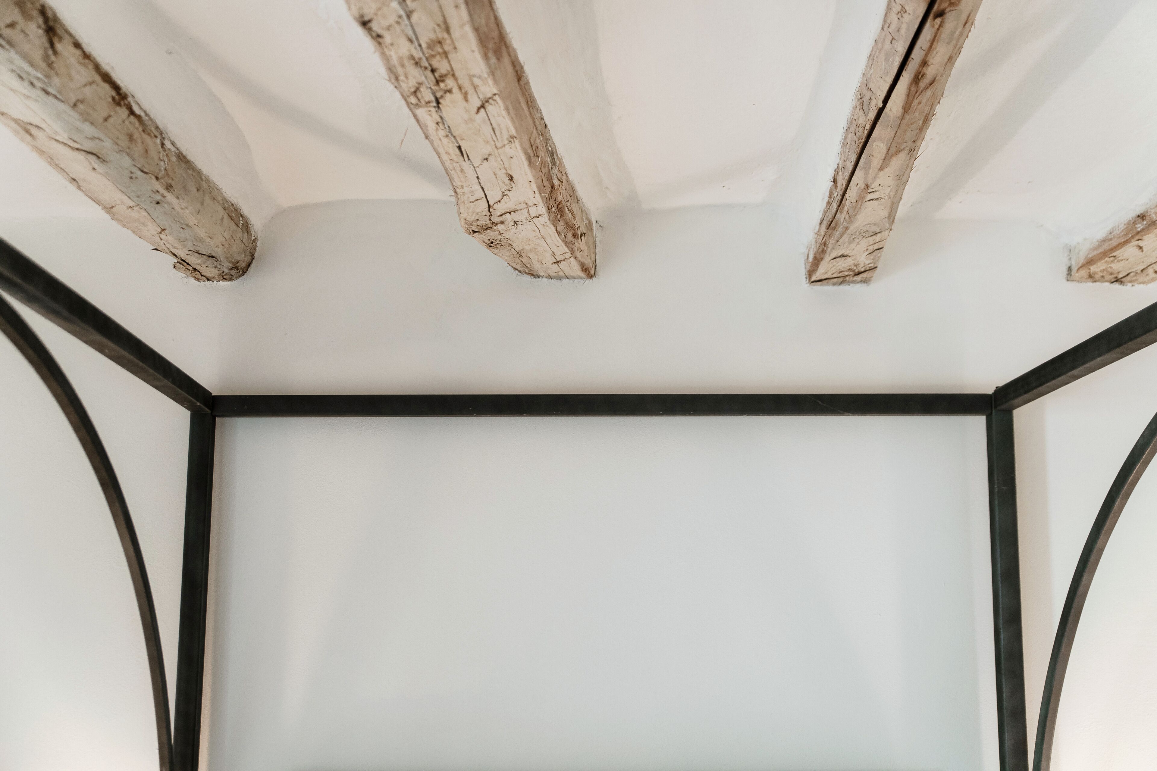 A room with a white ceiling and exposed wooden beams.