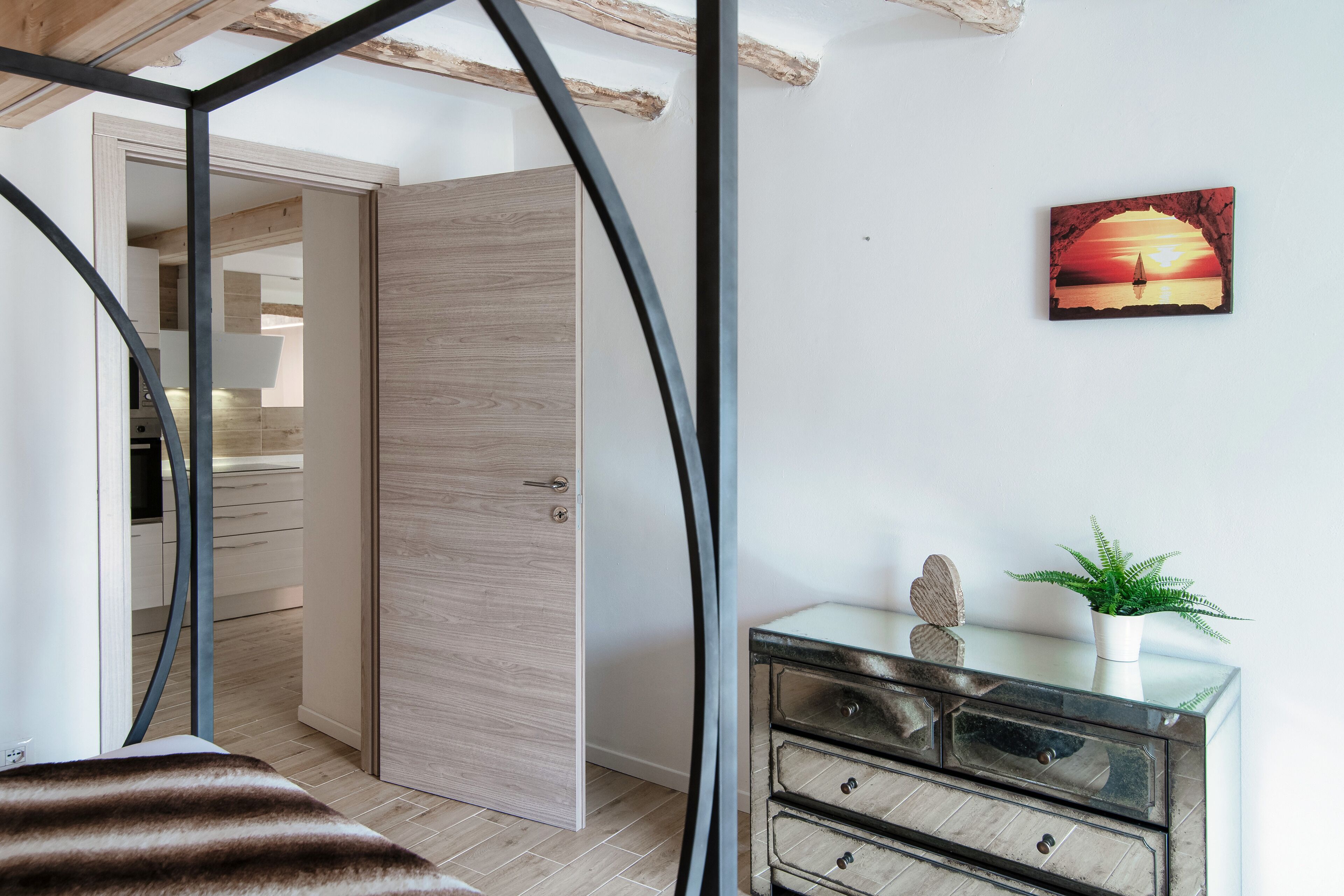 Ein Schlafzimmer mit Bett, Kommode, Tür und einem an der Wand hängenden Bild.