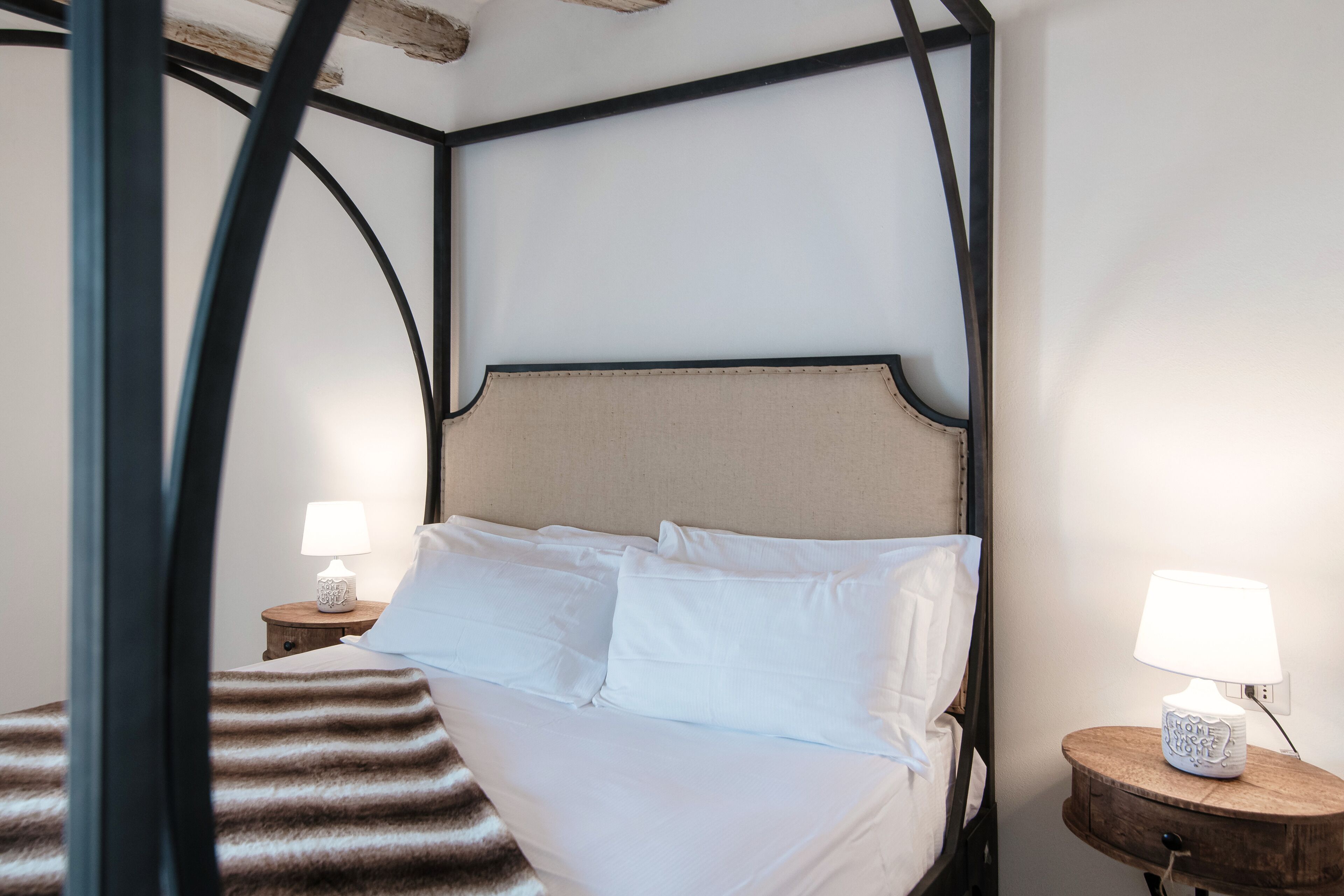A bedroom with a bed, two bedside tables with lamps, and a wooden headboard.