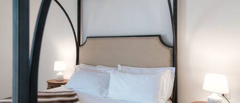 A bedroom with a bed, two bedside tables with lamps, and a wooden headboard.